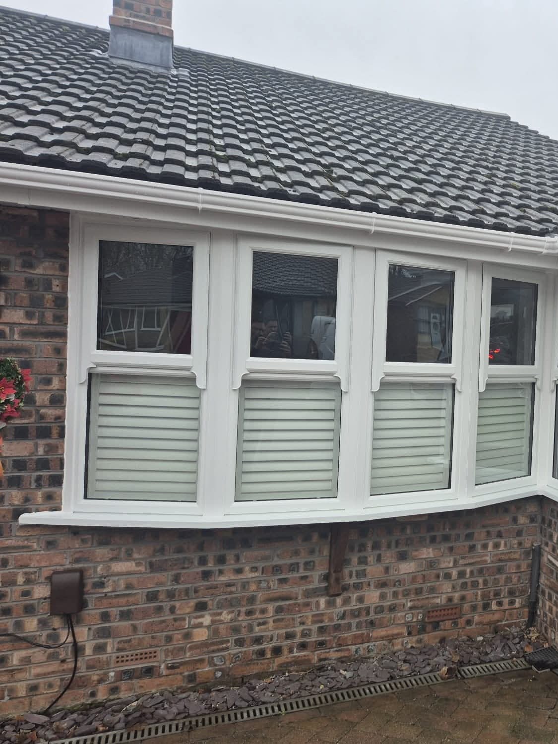 Home White uPVC bay window with shutters on a brick bungalow